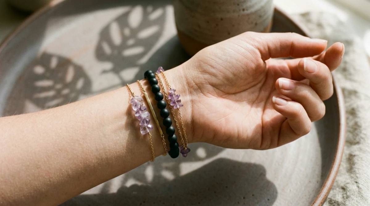 Stacked minimalist gemstone bracelets on a model's wrist, illustrating the crystal bracelet left hand meaning for reception and guidelines for wearing crystals on the right wrist for projection.