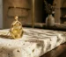 An architectural gold rutilated quartz pendant on ivory travertine, showcasing gold crystal jewelry styled for earth-toned outfits.